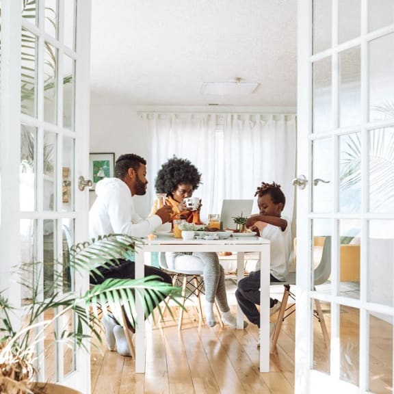 people sitting around a table eating at a laptop