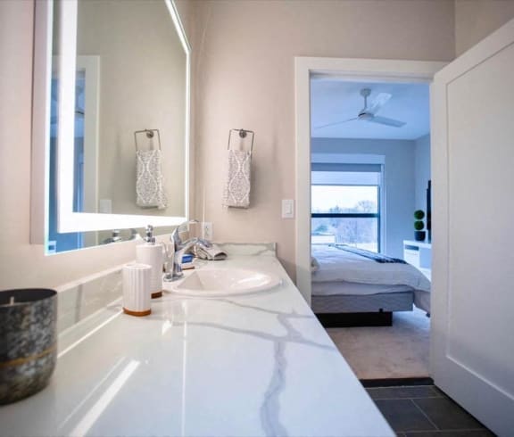 a bathroom with a sink and a mirror and a bedroom with a bed