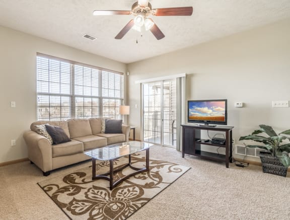 Living room with ceiling fan, patio and large windows in 1 bedroom apartment for rent at Stone Ridge Estates