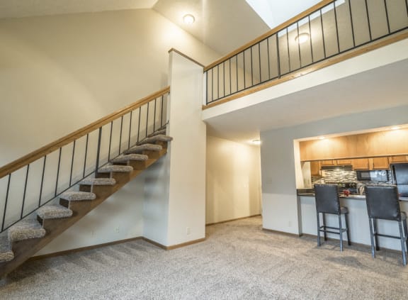 a staircase leading to the loft area of an apartment above a kitchen and a bar