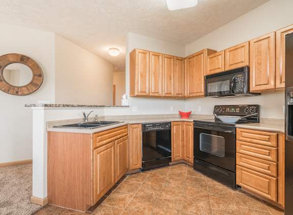 Large kitchen with black appliances and dark tan cabinets