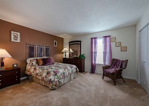 A bedroom with a floral bedspread and a chair.