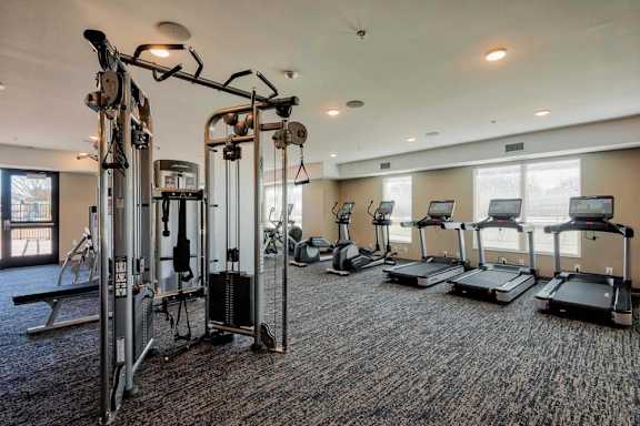 A gym with a variety of equipment including treadmills, weights, and exercise machines.
