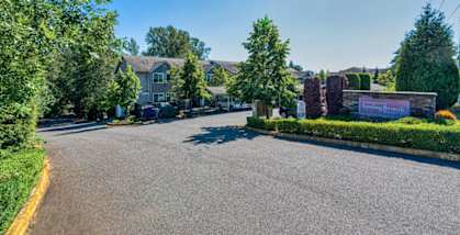 a street view of a house with a driveway and trees