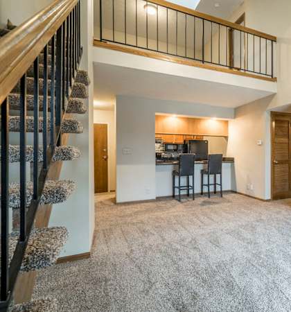the living room and kitchen of an apartment with a loft