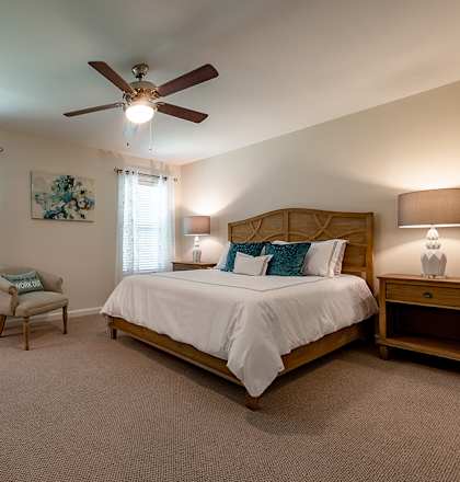 A bedroom with a large bed and a ceiling fan.