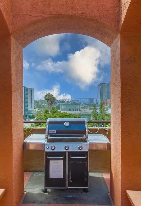 A BBQ grill is in the middle of a patio with a view of the city.