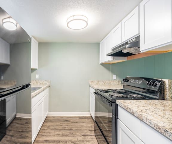 a kitchen with white cabinets and black appliances at Bella Mar Apartments