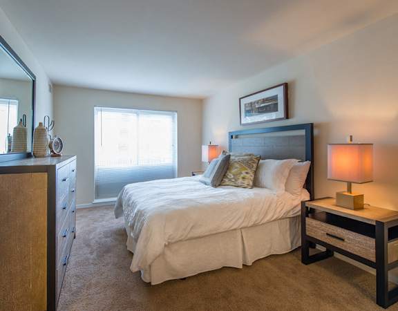 A bedroom with a bed, nightstand, and a dresser.
