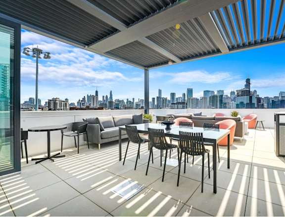 A patio with a table and chairs overlooking a city skyline.