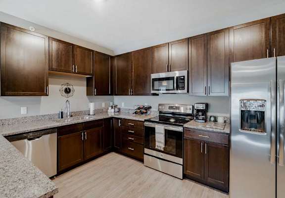 A modern kitchen with brown cabinets and stainless steel appliances