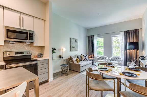 a living room with a kitchen and a dining table  at North Square at The Mill District in North Amherst, MA