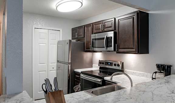 A kitchen with a white fridge and a stainless steel sink.