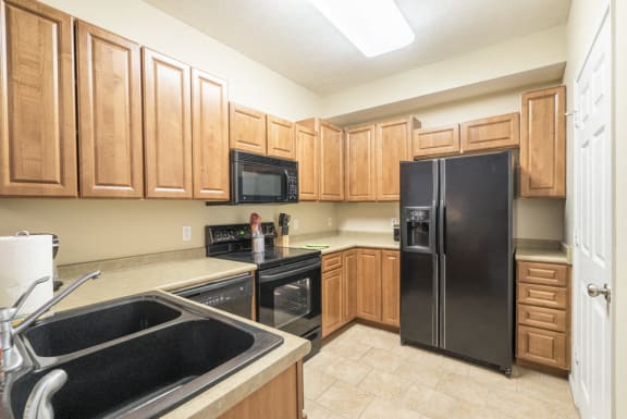 a kitchen with black appliances and warm wooden cabinets