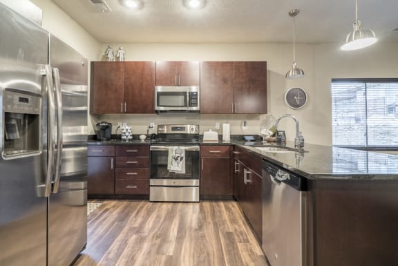 U-shaped kitchen with cherry brown cabinets and stainless steel appliances