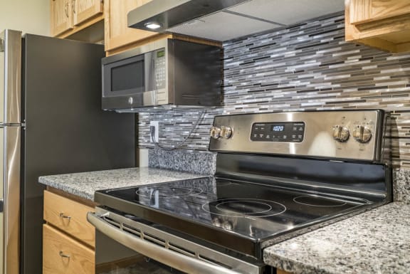 Stainless steel stove in remodeled kitchen with granite counters and tile backsplash