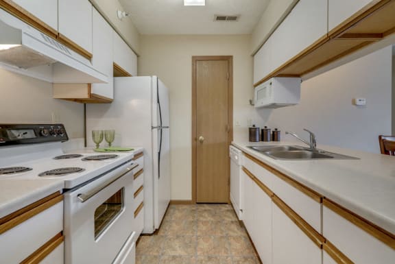 Galley style kitchen with white cabinets and appliances