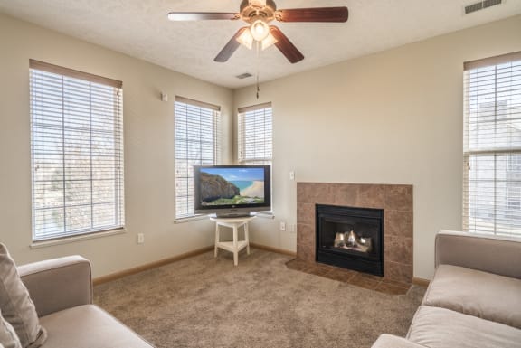 Living room with ceiling fan, sofa, TV, and fireplace.