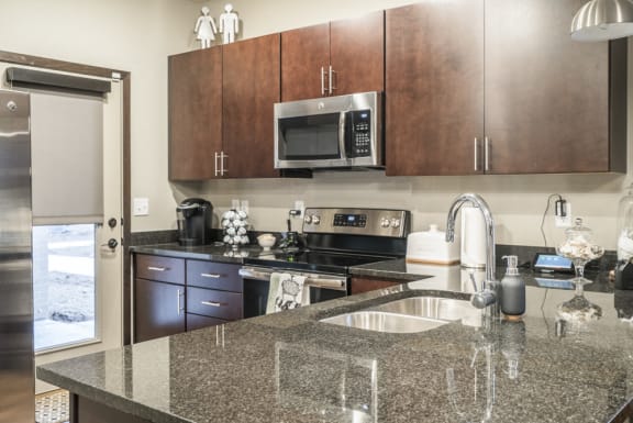 Kitchen with dark granite counters, stainless steel appliances, and warm cherry cabinets