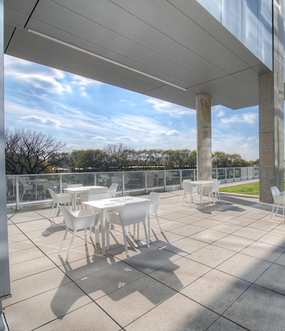A patio with tables and chairs is covered by a roof.