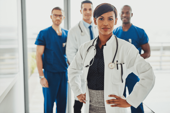 a woman in a white lab coat with a stethoscope around her neck stands in front