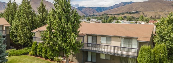 An aerial view of apartments with trees in the foreground and mountains in the background.at Cedarwood, Washington