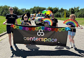 A group of people holding a banner that says "centerspace" and rainbow flags.