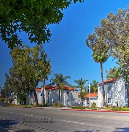 A row of white houses with trees in front.