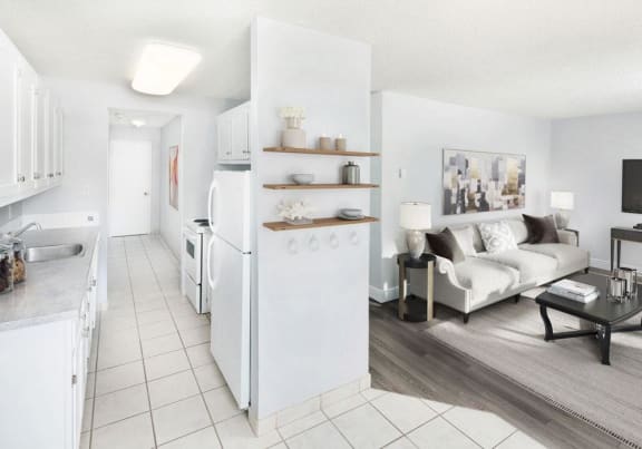 View of the kitchen and living room with a fridge and stove, and a couch and lamp.