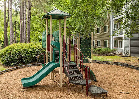 A playground with a green slide and a red and green play structure.