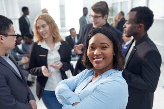A group of business people are standing in a circle in a meeting room.