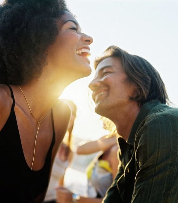 a couple of women laughing while standing on the beach