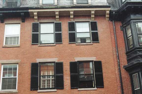 A red brick building with black shutters on the windows.