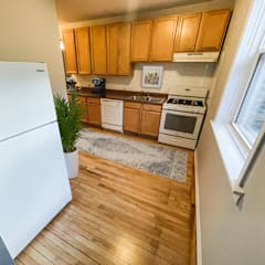 a kitchen with wooden floors and wooden cabinets and a white refrigerator