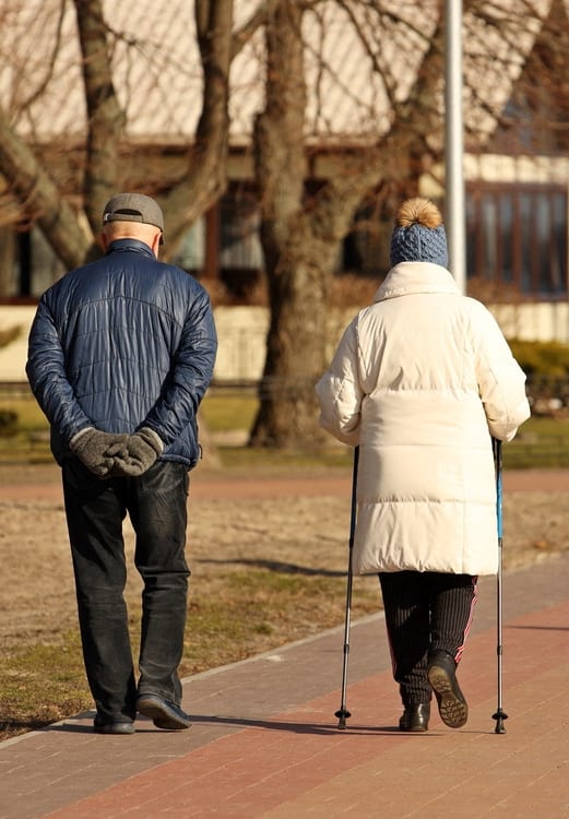 a man and a woman walking down a sidewalk with sticks
