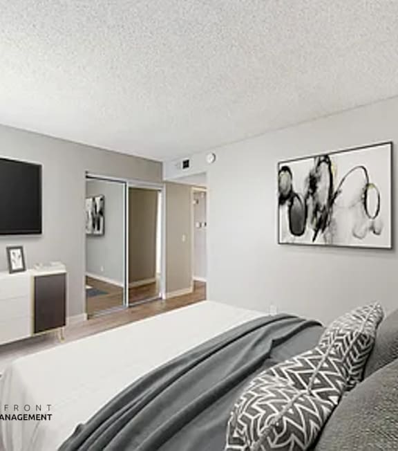 A well-lit bedroom with a large bed and a painting on the wall.