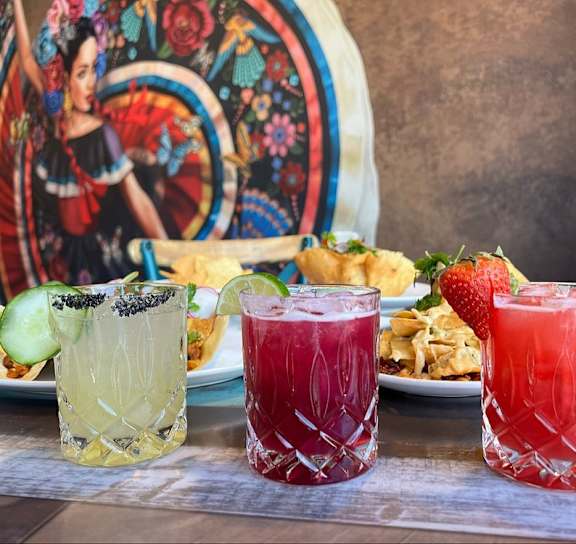 Three glasses of different colored drinks are on a table.