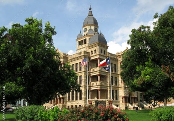a large building with a clock tower and a flag on the front at Urban Square, Denton, TX