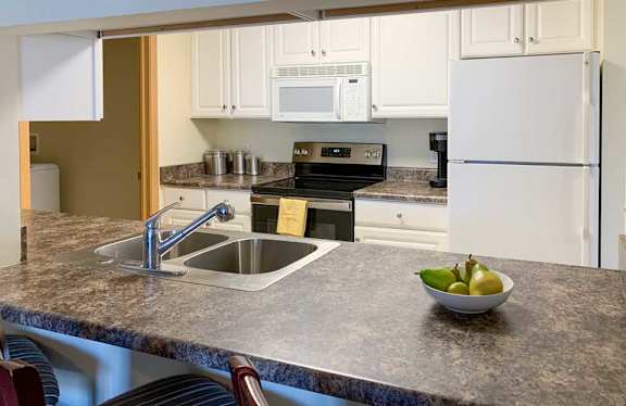 A kitchen with white cabinets and a white fridge.