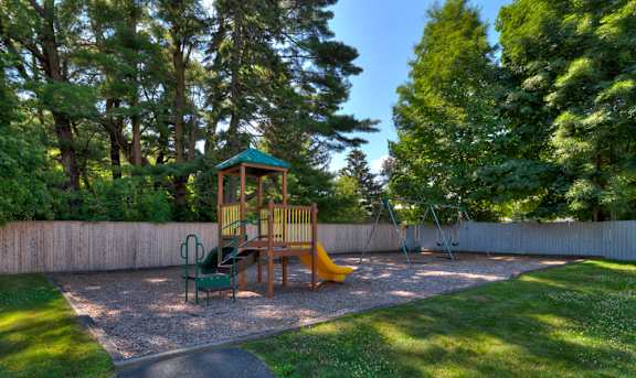A playground with a slide and a wooden swing set at Pine Grove Apartments, Taunton, 02780