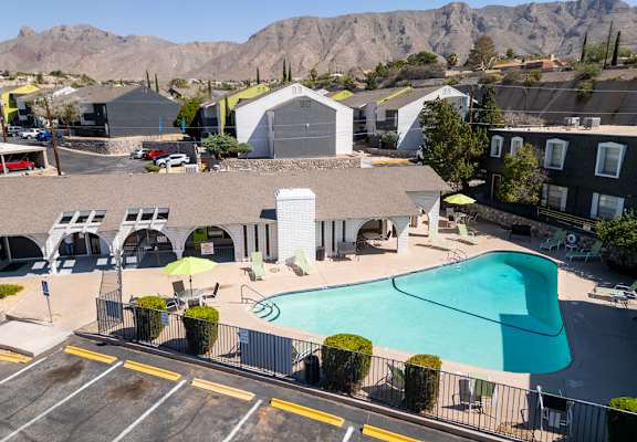 A parking lot is surrounded by buildings and a mountain in the background.