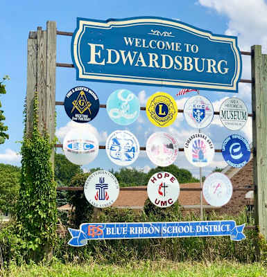 a welcome to edwardsburg sign with a variety of badges on it