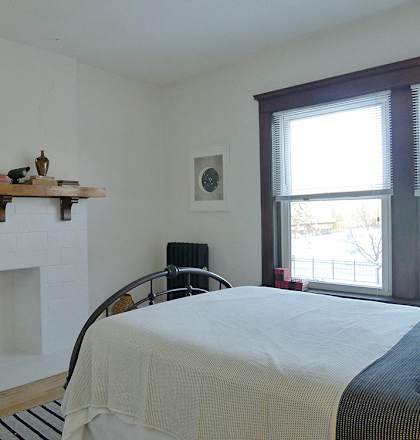 a bedroom with a bed and a fireplace and a window
