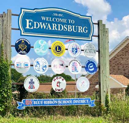 a welcome to edwardsburg sign with a variety of badges on it