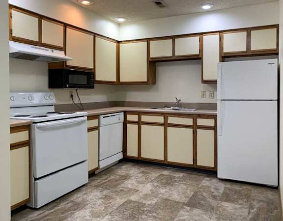 a kitchen with white appliances and white and wooden cabinets