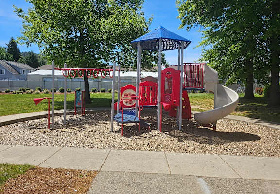 A playground with a blue canopy and red and white slides.