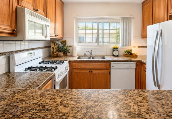 A kitchen with granite countertops and white appliances.