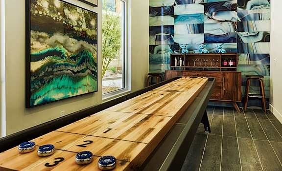 a game room with a shuffleboard table and paintings on the wall at 56 North, Phoenix, 85054