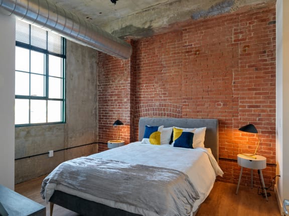 Bedroom with Exposed Brick and Concrete at Montgomery Mill Apartments in Windsor Locks, CT