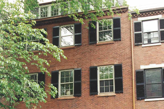 A red brick building with black shutters on the windows.